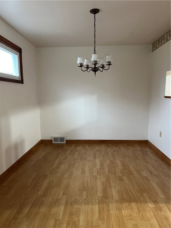 empty room featuring hardwood / wood-style flooring and a notable chandelier