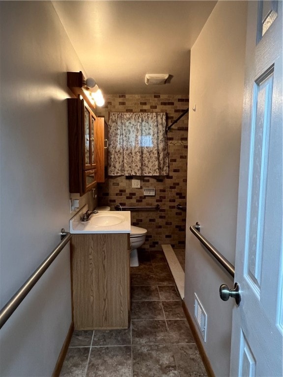 bathroom with tile patterned flooring, toilet, vanity, and walk in shower