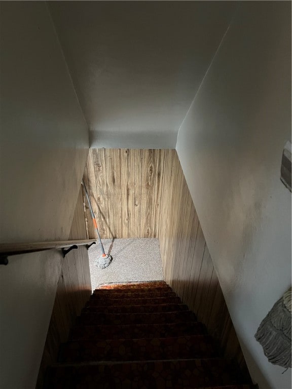 stairs featuring vaulted ceiling and wood walls