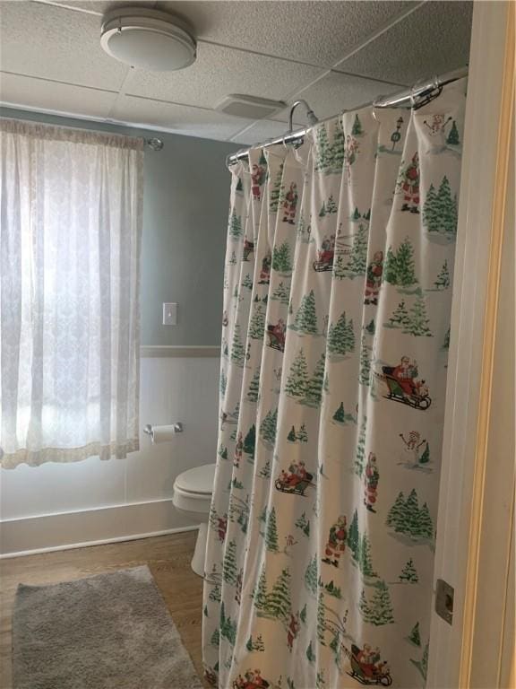 bathroom with a shower with curtain, a paneled ceiling, toilet, and hardwood / wood-style flooring