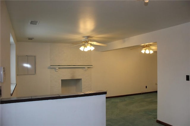 kitchen featuring dark colored carpet, ceiling fan, and a fireplace