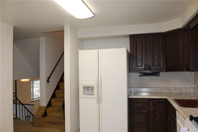 kitchen with dark brown cabinets, decorative backsplash, white appliances, and sink