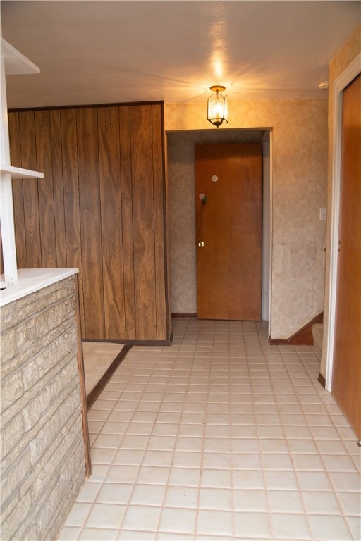 corridor with wooden walls and light tile patterned flooring