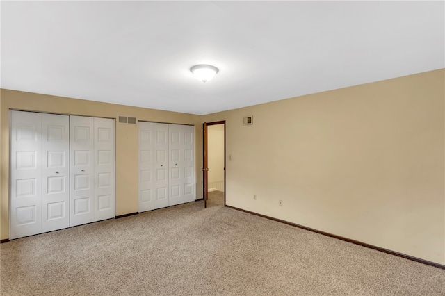 unfurnished bedroom featuring carpet and two closets