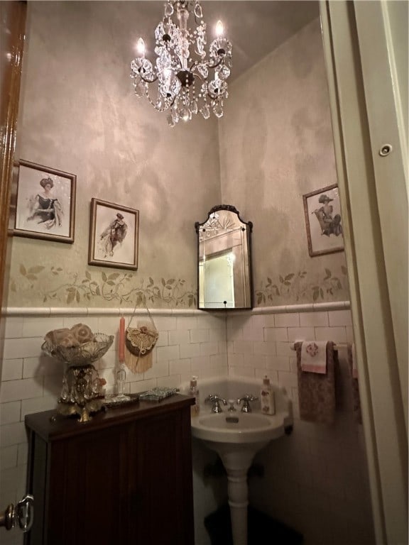 bathroom with a notable chandelier and tile walls