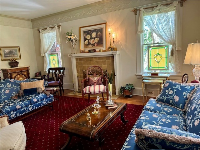 living room featuring hardwood / wood-style flooring, crown molding, and a tiled fireplace