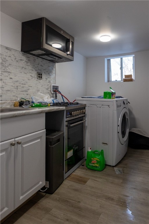 kitchen featuring white cabinetry, stainless steel appliances, tasteful backsplash, washer / clothes dryer, and light hardwood / wood-style floors