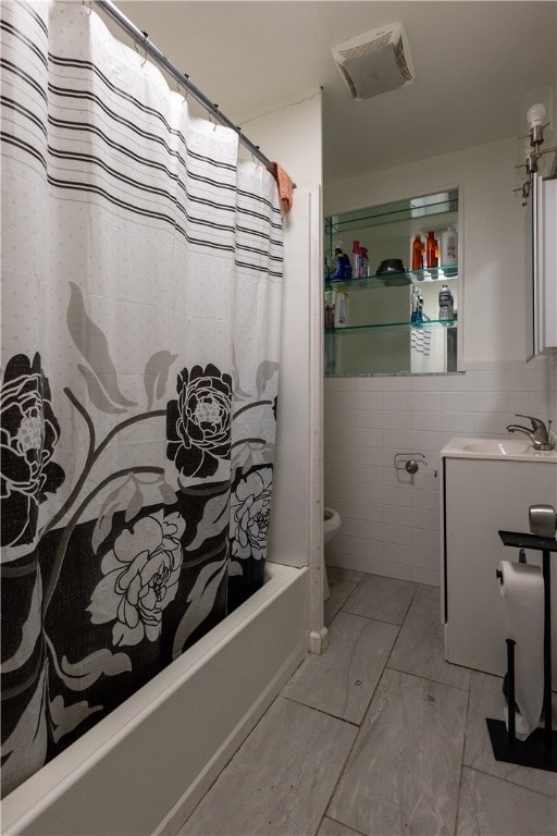 full bathroom with vanity, toilet, tile walls, and shower / tub combo