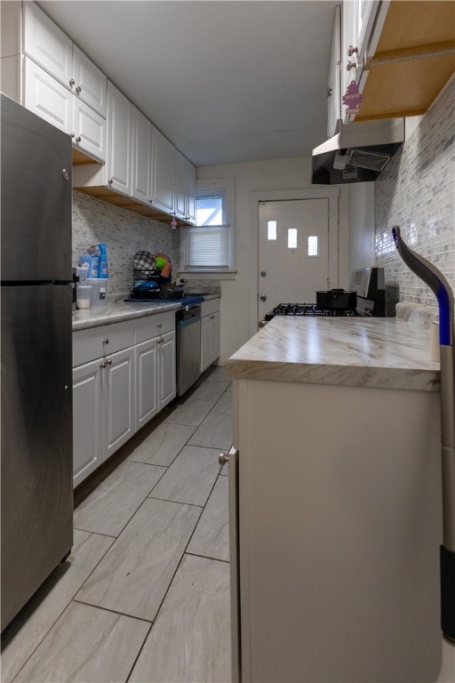 kitchen with backsplash, white cabinetry, stainless steel appliances, and exhaust hood