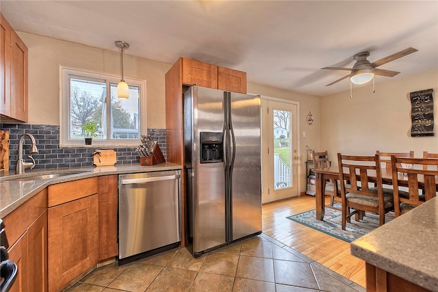 kitchen with decorative light fixtures, light wood-type flooring, stainless steel appliances, and a wealth of natural light