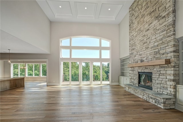 unfurnished living room with hardwood / wood-style flooring, a fireplace, and a high ceiling