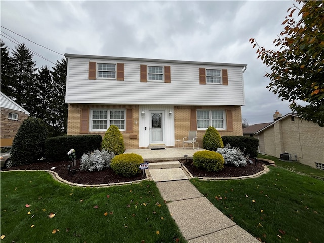 colonial house featuring a front yard and central AC unit