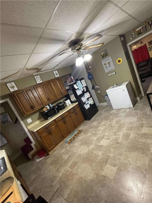 kitchen featuring ceiling fan and a drop ceiling