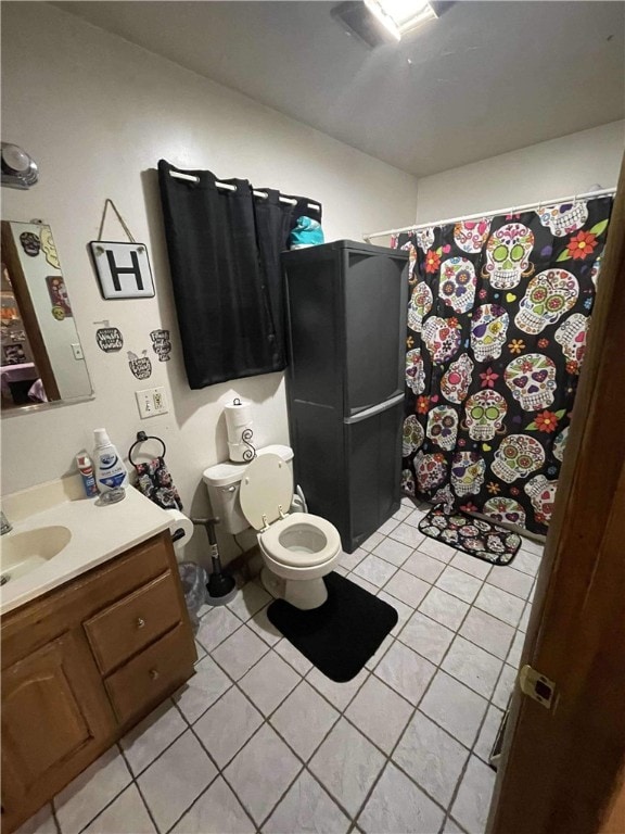 bathroom with tile patterned flooring, vanity, toilet, and walk in shower