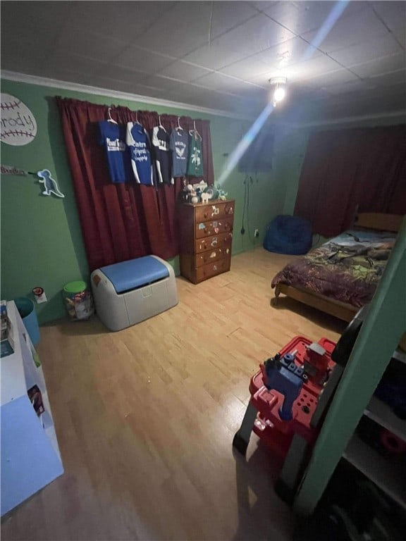 bedroom featuring crown molding, hardwood / wood-style floors, and a drop ceiling