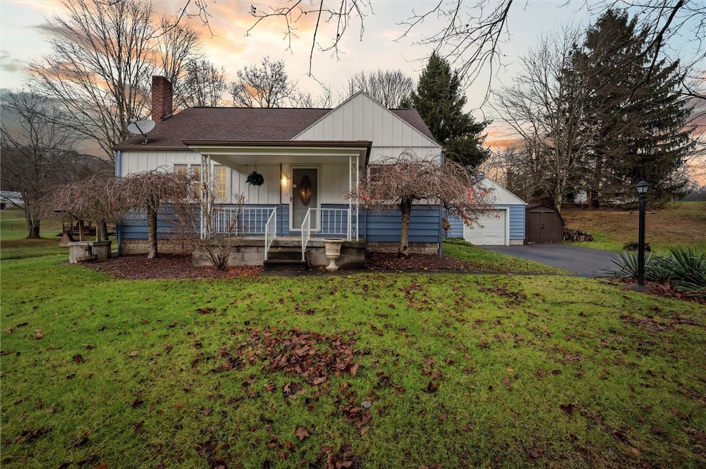 view of front of property with a lawn, a porch, an outbuilding, and a garage