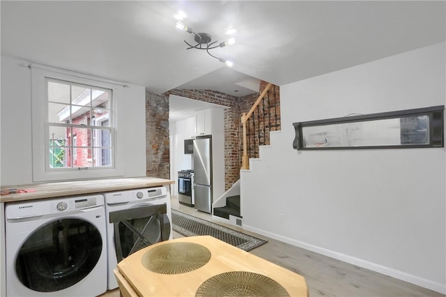 laundry room with washer / dryer, light wood-type flooring, and brick wall