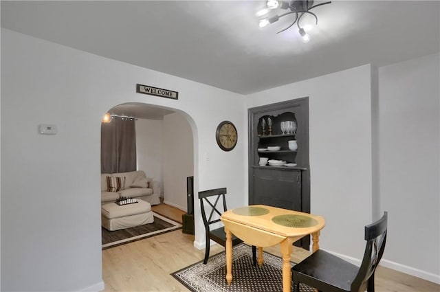 1402 Bingham St, South Side, PA 15203 - dining space with arched walkways, light wood-style floors, and baseboards