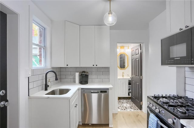 1402 Bingham St, South Side, PA 15203 - kitchen featuring stainless steel appliances, a sink, light countertops, white cabinets, and tasteful backsplash