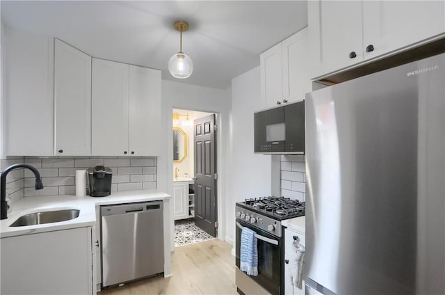 1402 Bingham St, South Side, PA 15203 - kitchen featuring stainless steel appliances, a sink, white cabinets, light wood finished floors, and decorative backsplash