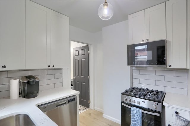 kitchen featuring tasteful backsplash, white cabinets, hanging light fixtures, and appliances with stainless steel finishes