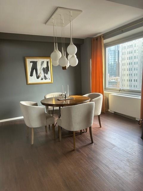 dining room featuring radiator, attic access, baseboards, and wood finished floors