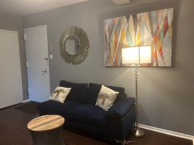 living room with baseboards and dark wood-type flooring