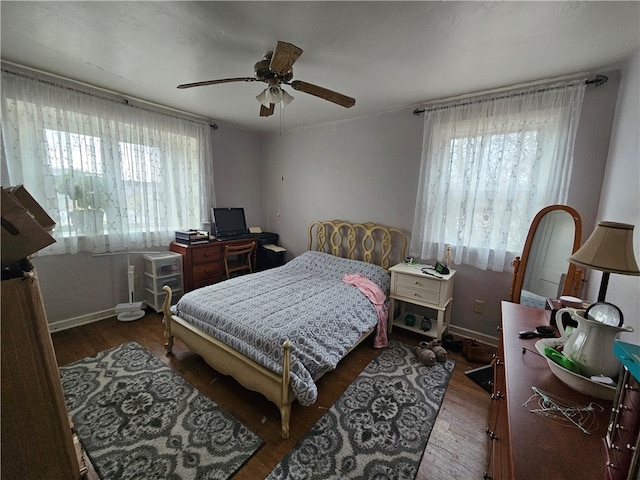 bedroom featuring multiple windows, dark wood-type flooring, and ceiling fan