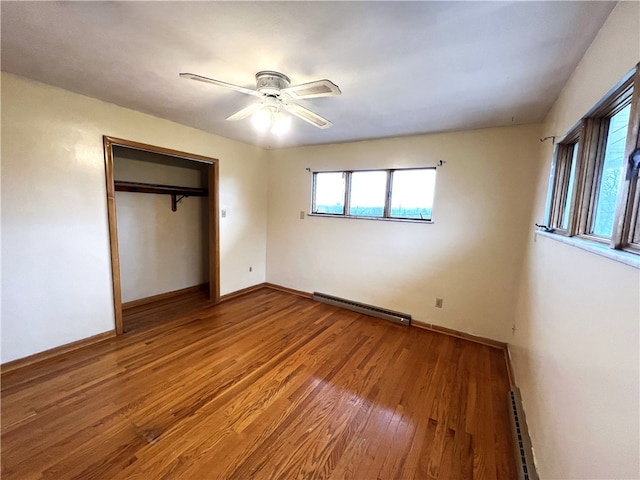 unfurnished bedroom with hardwood / wood-style flooring, ceiling fan, baseboard heating, and a closet