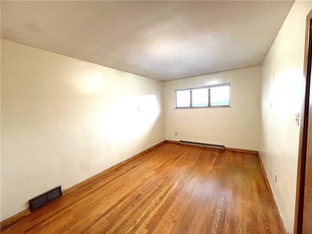 unfurnished room with hardwood / wood-style flooring and a baseboard heating unit