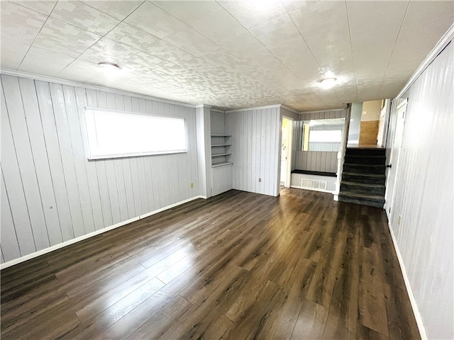 interior space with a wealth of natural light, dark hardwood / wood-style flooring, and wooden walls