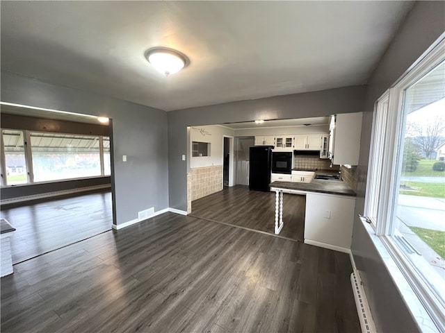 kitchen featuring decorative backsplash, oven, white cabinetry, and dark wood-type flooring