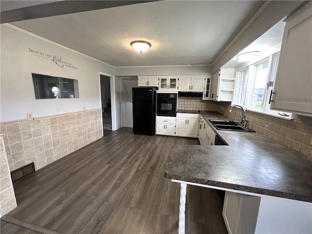 kitchen featuring kitchen peninsula, decorative backsplash, sink, black appliances, and white cabinetry