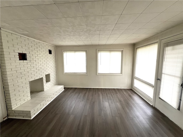 unfurnished living room featuring a brick fireplace and dark wood-type flooring