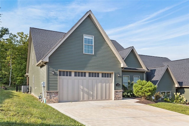 view of front of home featuring a front lawn, a garage, and central AC