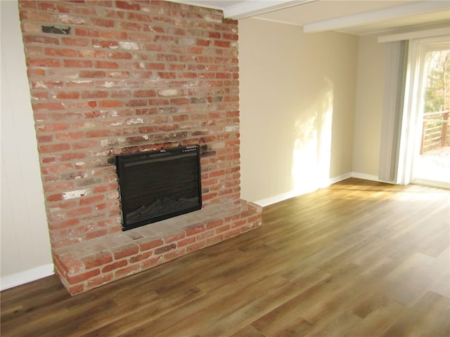 unfurnished living room featuring a fireplace, beamed ceiling, and wood-type flooring