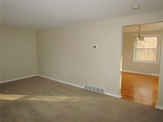 spare room featuring hardwood / wood-style flooring, a notable chandelier, and a baseboard radiator