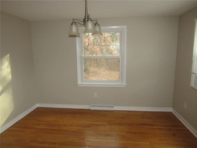 unfurnished dining area featuring hardwood / wood-style flooring and an inviting chandelier