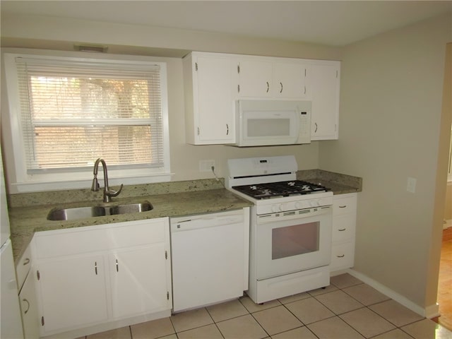 kitchen with light stone counters, white appliances, sink, light tile patterned floors, and white cabinets