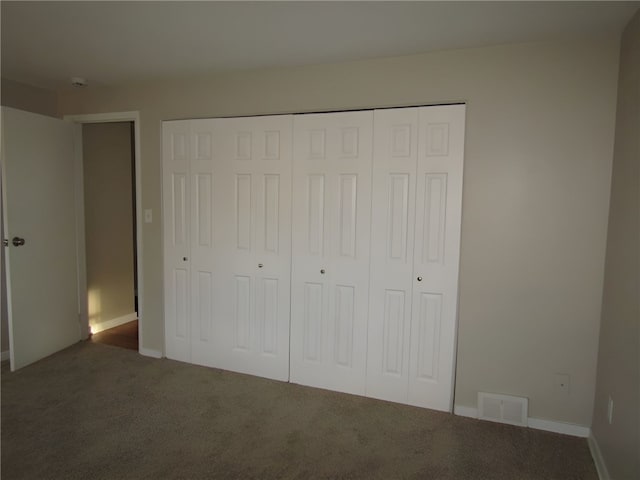 unfurnished bedroom featuring dark colored carpet and a closet