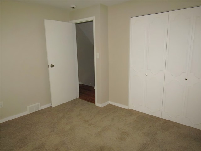 unfurnished bedroom featuring light carpet and a closet