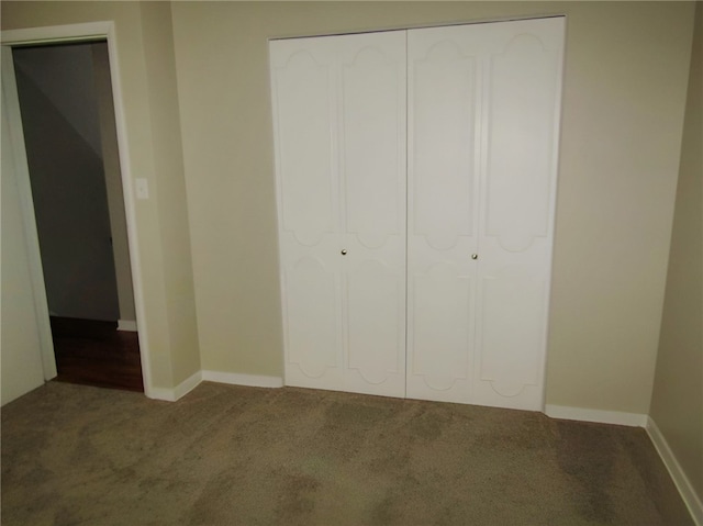 unfurnished bedroom featuring dark carpet and a closet