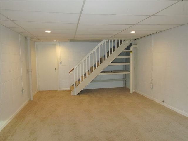 basement with a paneled ceiling and carpet