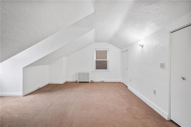 additional living space with carpet floors, a textured ceiling, radiator, and vaulted ceiling