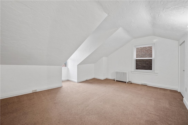 additional living space with a textured ceiling, radiator heating unit, carpet, and lofted ceiling