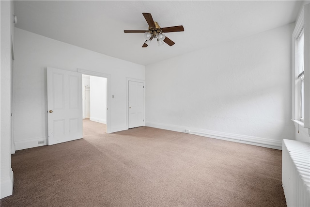 spare room featuring carpet, ceiling fan, and radiator heating unit