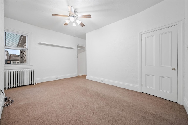 unfurnished bedroom with ceiling fan, radiator heating unit, and light carpet