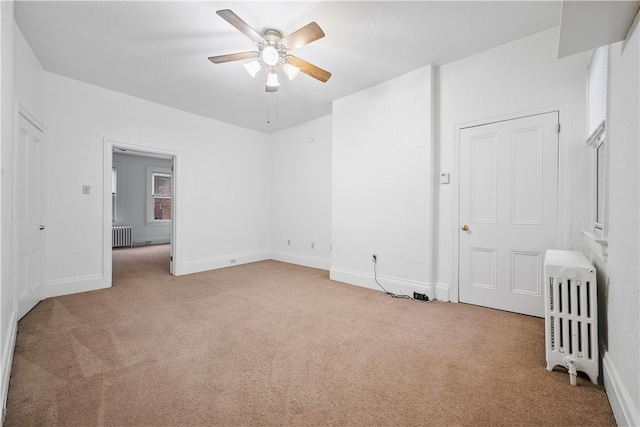 unfurnished bedroom featuring light carpet, radiator heating unit, and ceiling fan