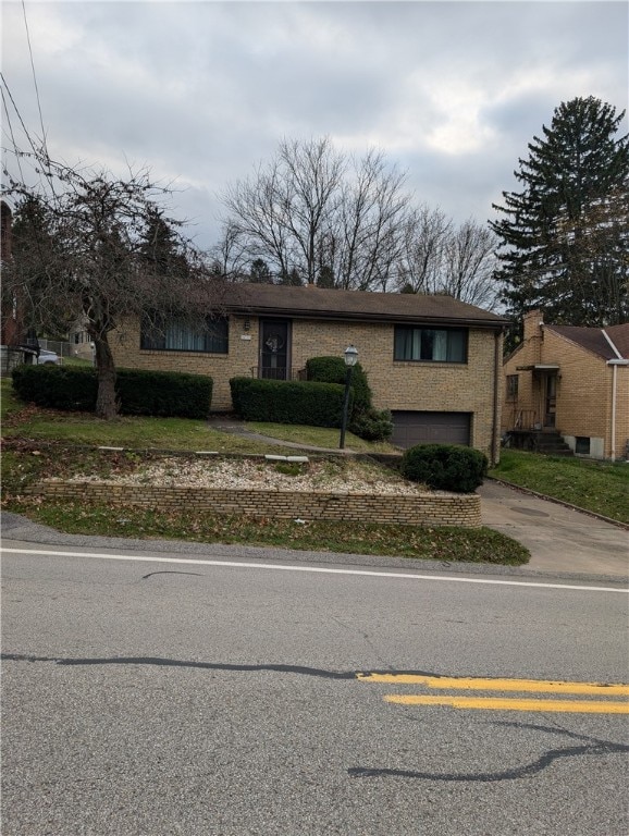 view of front of house with a garage, concrete driveway, and brick siding