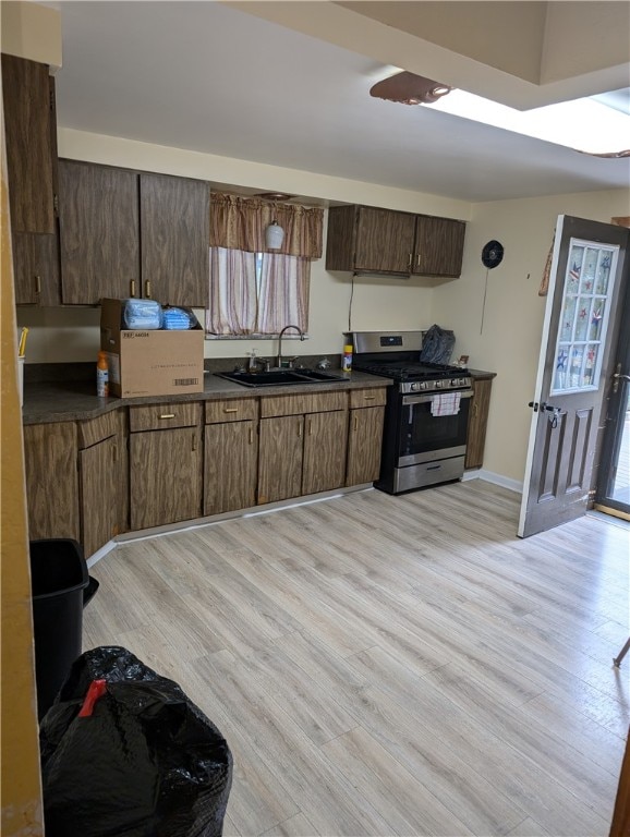 kitchen featuring sink, light wood-type flooring, dark brown cabinetry, and stainless steel range with gas stovetop